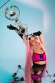 Person with pink hair and black gloves holding a decorative object against a light blue background.
