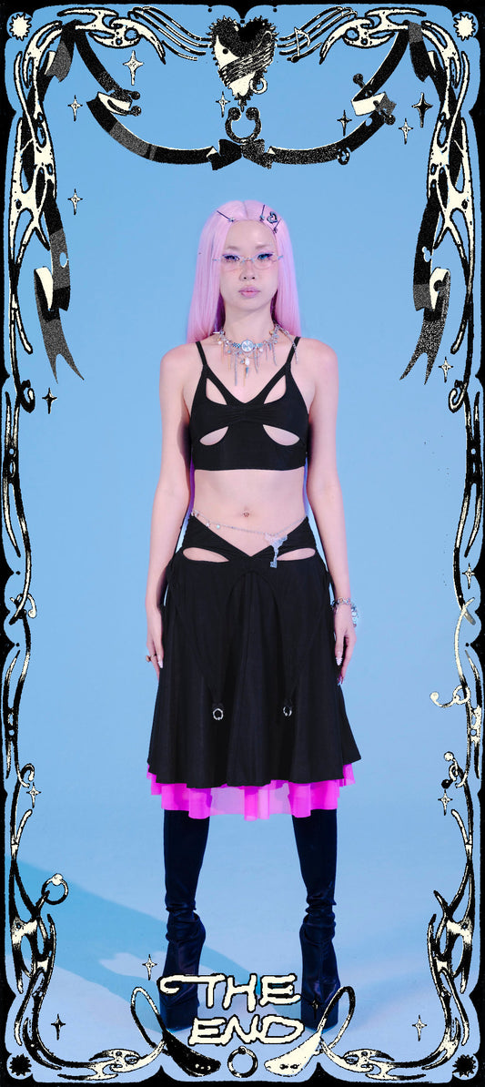 Person wearing a black outfit with pink accents against a blue background, framed by decorative elements.