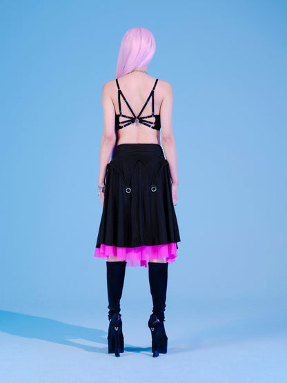 Person wearing a black dress with pink trim on a light blue background