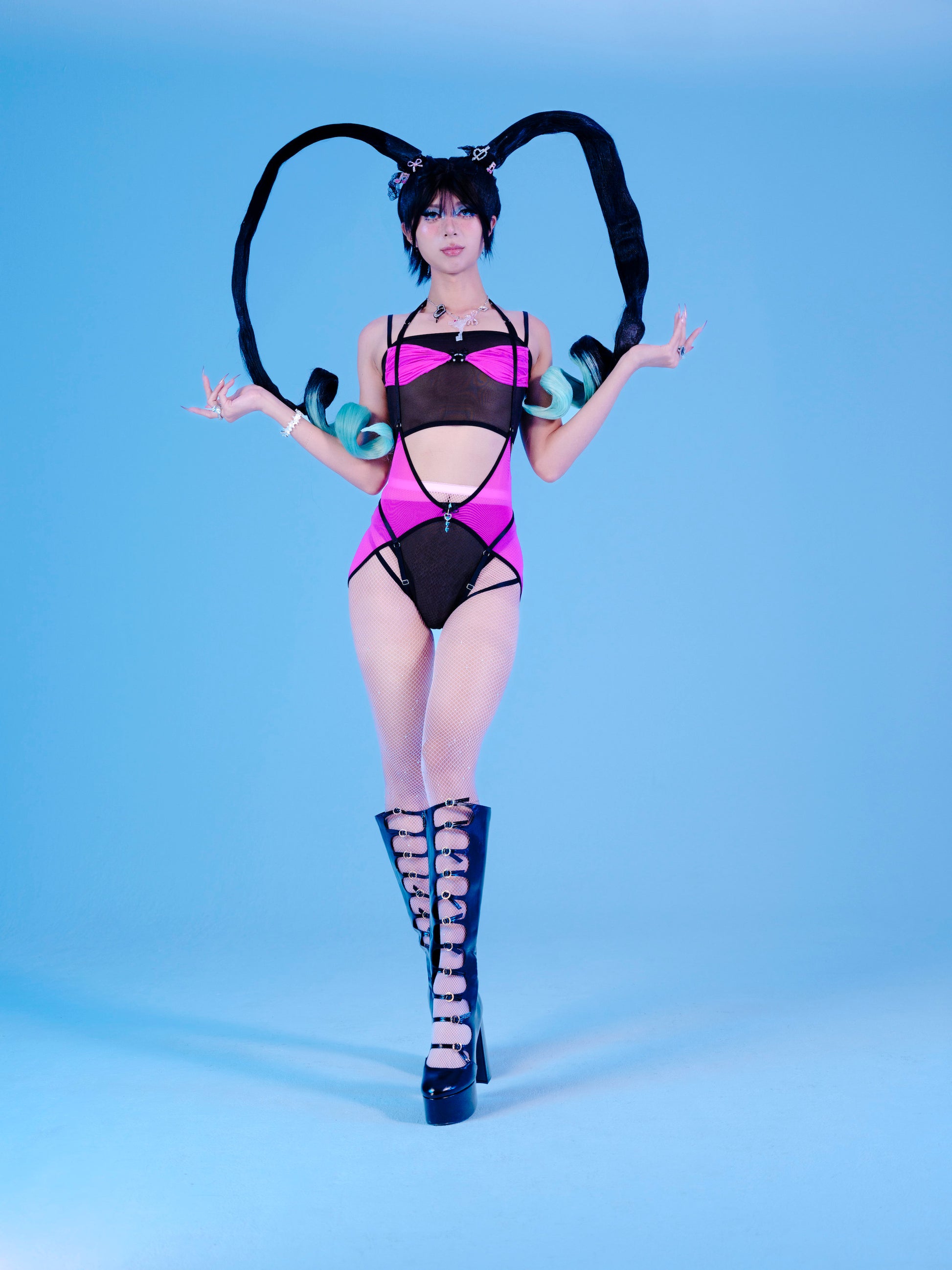 Person wearing a black and purple outfit with high-heeled boots on a blue background