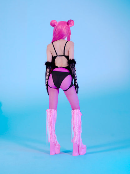Person with pink hair styled like buns, wearing a black outfit with cut-out design and pink high boots on a blue background.